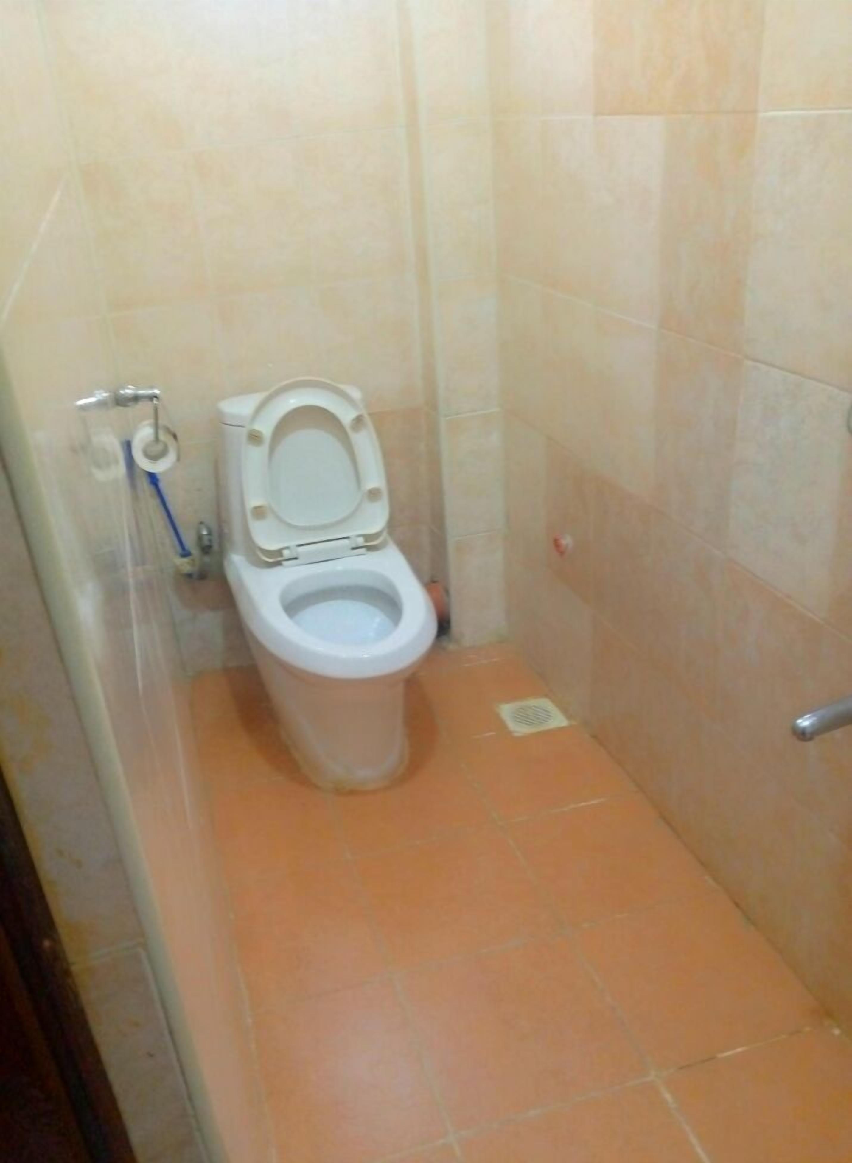 A small, tiled bathroom with a toilet, a hand dryer, and a paper towel dispenser.