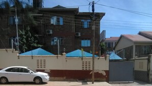 A multi-story building with a red and white facade, several windows, and a parked white car in front. - Metropak Hotel Breweries (Kisumu)