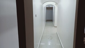 A narrow, well-lit hallway with white walls and a tiled floor, leading to a door at the end. - Metropak Hotel Breweries (Kisumu)