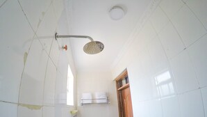 A bathroom with white tiles, a shower, a sink, and a towel rack. - Metropak Hotel Breweries (Kisumu)