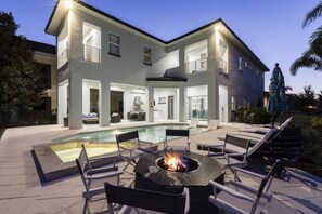 A modern house with a swimming pool, outdoor seating, and a fire pit. - Luxury 6 Bedroom Villa on Reunion Resort and Spa, Orlando Villa 3095 (Kissimmee)