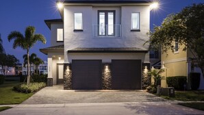 Una casa a due piani con garage, dettagli in pietra e un ingresso principale ben illuminato.