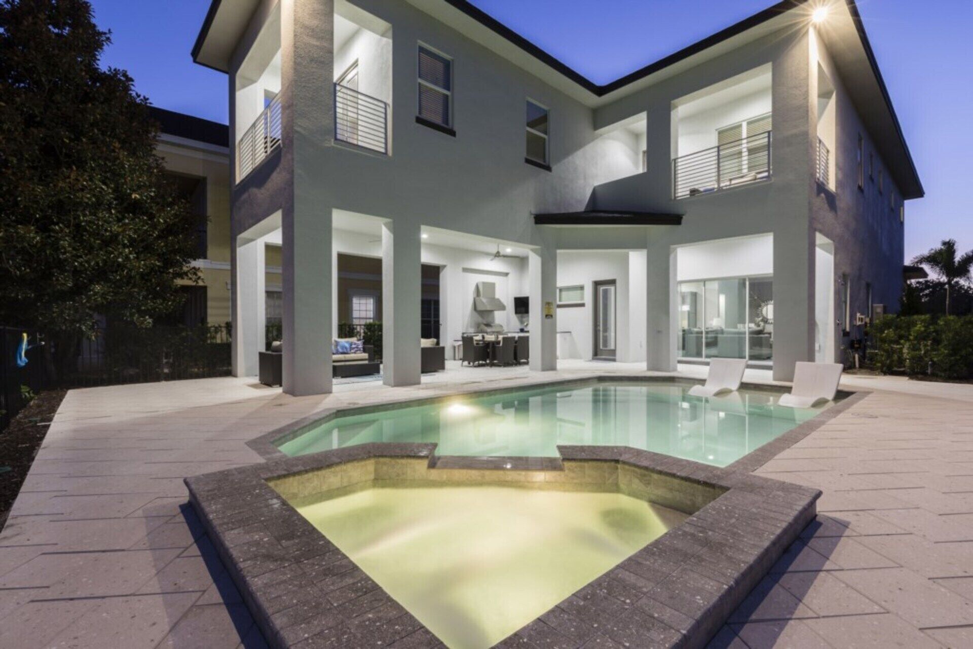 Ein modernes, zweistöckiges Haus mit Schwimmbad, Außenbereich und überdachter Terrasse.