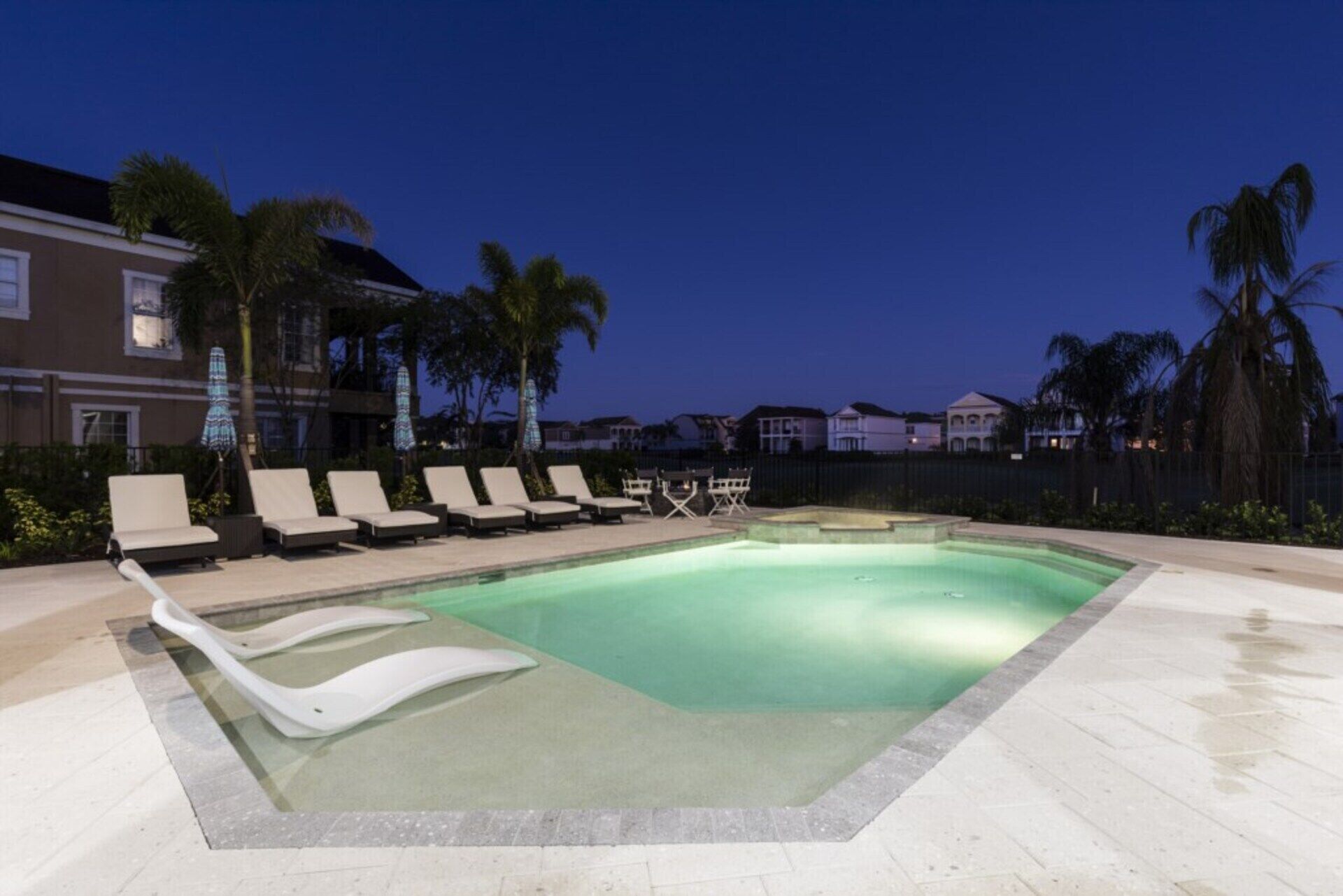A swimming pool with lounge chairs and palm trees.