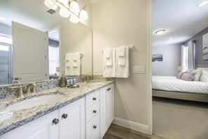 A bathroom with a granite countertop, white cabinets, and a large mirror. There are two white towels hanging on the wall. - Villa in Encore Resort at Reunion 3443 (Kissimmee)