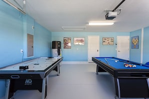 Ett rum med ett biljardbord, ett fotbollsspel och en kaffemaskin.