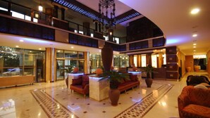 A spacious lobby with a high ceiling, a central seating area with sofas, a large vase, and a reception desk. - Noxinn Club Hotel  (Alanya)