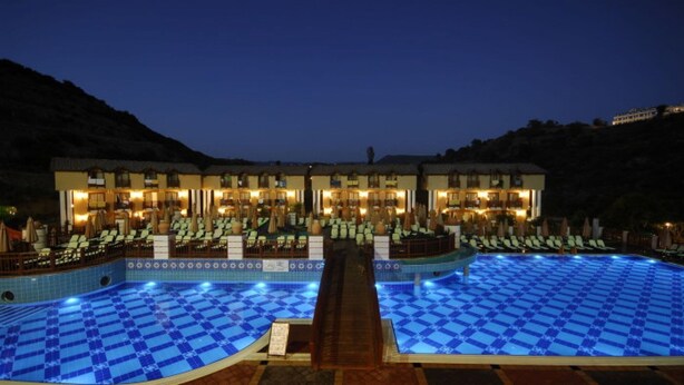 A hotel with a large pool, multiple lounge areas, and a well-lit building facade. - Noxinn Club Hotel  (Alanya)