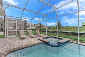 Una piscina exterior techada con sillas de descanso y un jacuzzi.