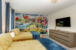 Une chambre avec deux lits, une grande fresque murale, une télévision et une commode.