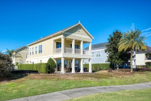 A two-story house with a balcony, a covered porch, and a well-maintained lawn.