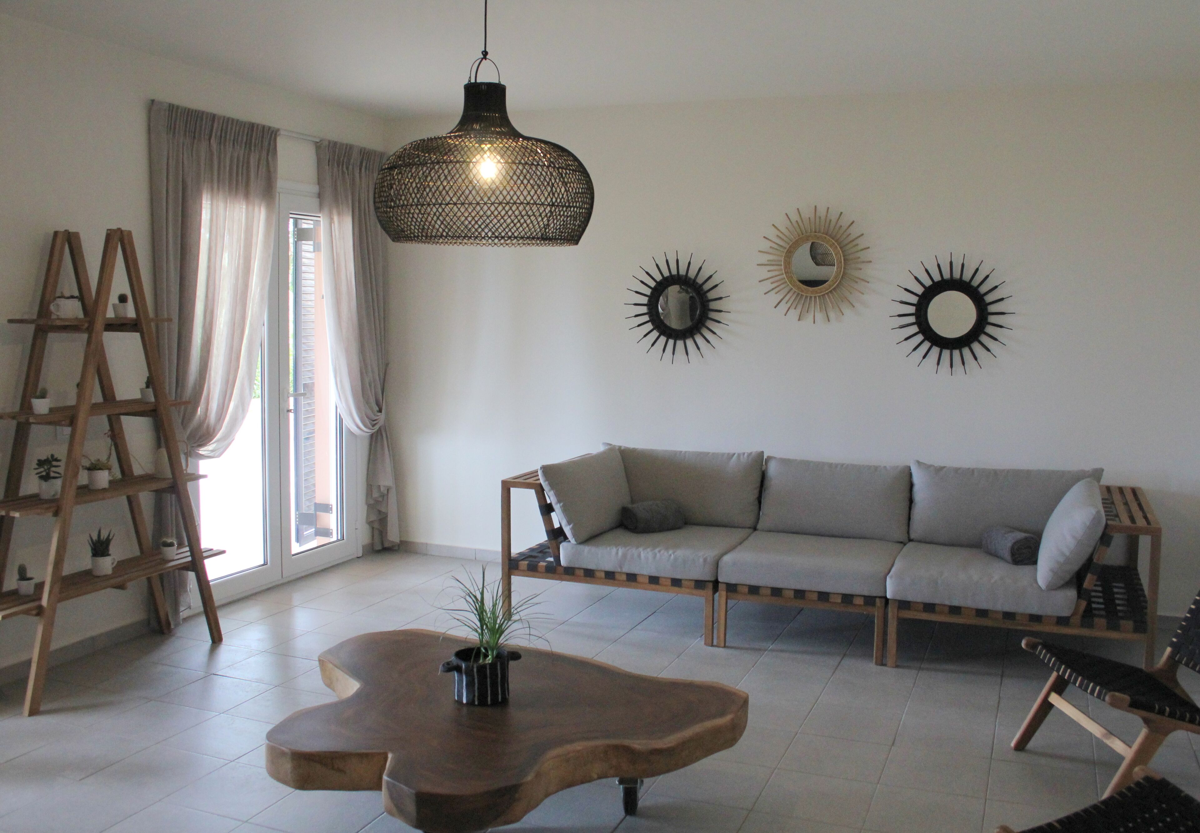 A living room with a sofa, a wooden coffee table, a hanging light fixture, and decorative wall mirrors.