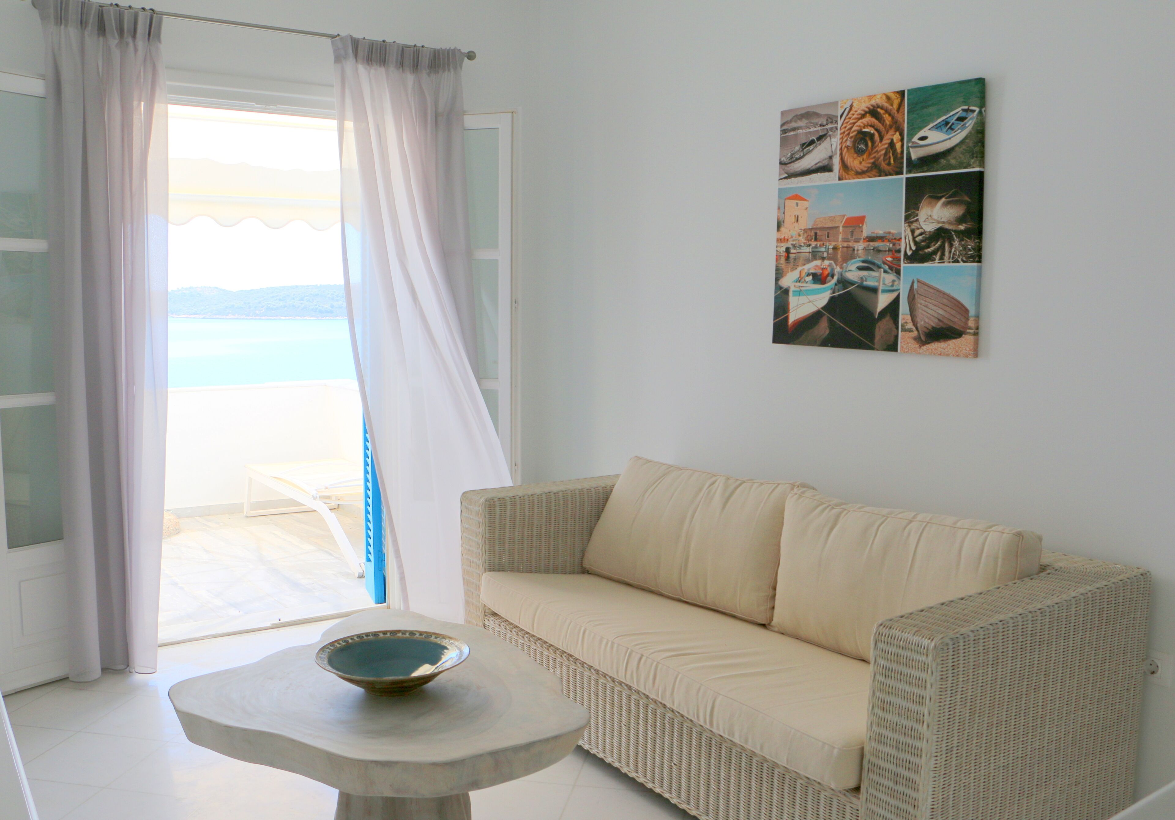 Una habitación con un sofá color beige, una mesa con un tazón y una pared decorada con motivos náuticos.