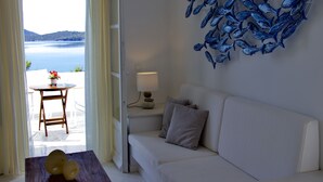 Ett modernt vardagsrum med en vit soffa, ett bord med en lampa och en väggdekoration som föreställer blå fiskar.