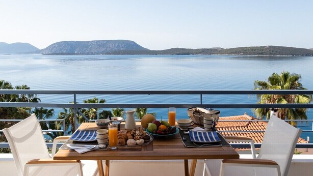 Ett bord dukat med frukostmat och utsikt över havet.