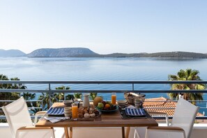 Una mesa servida con alimentos para el desayuno y vista al mar.