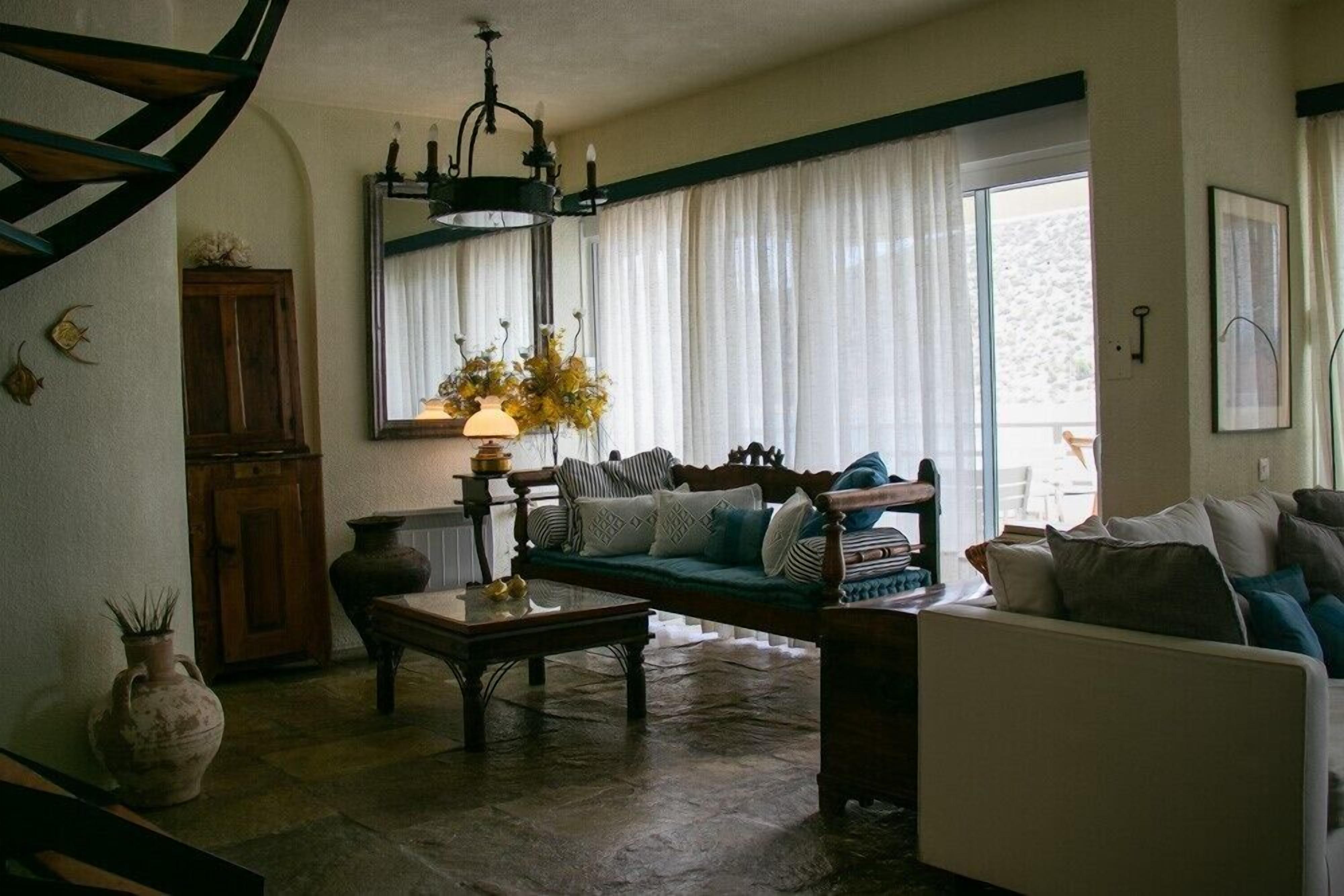 Un salón acogedor con un sofá de madera, una mesa de centro y un ventanal con cortinas.