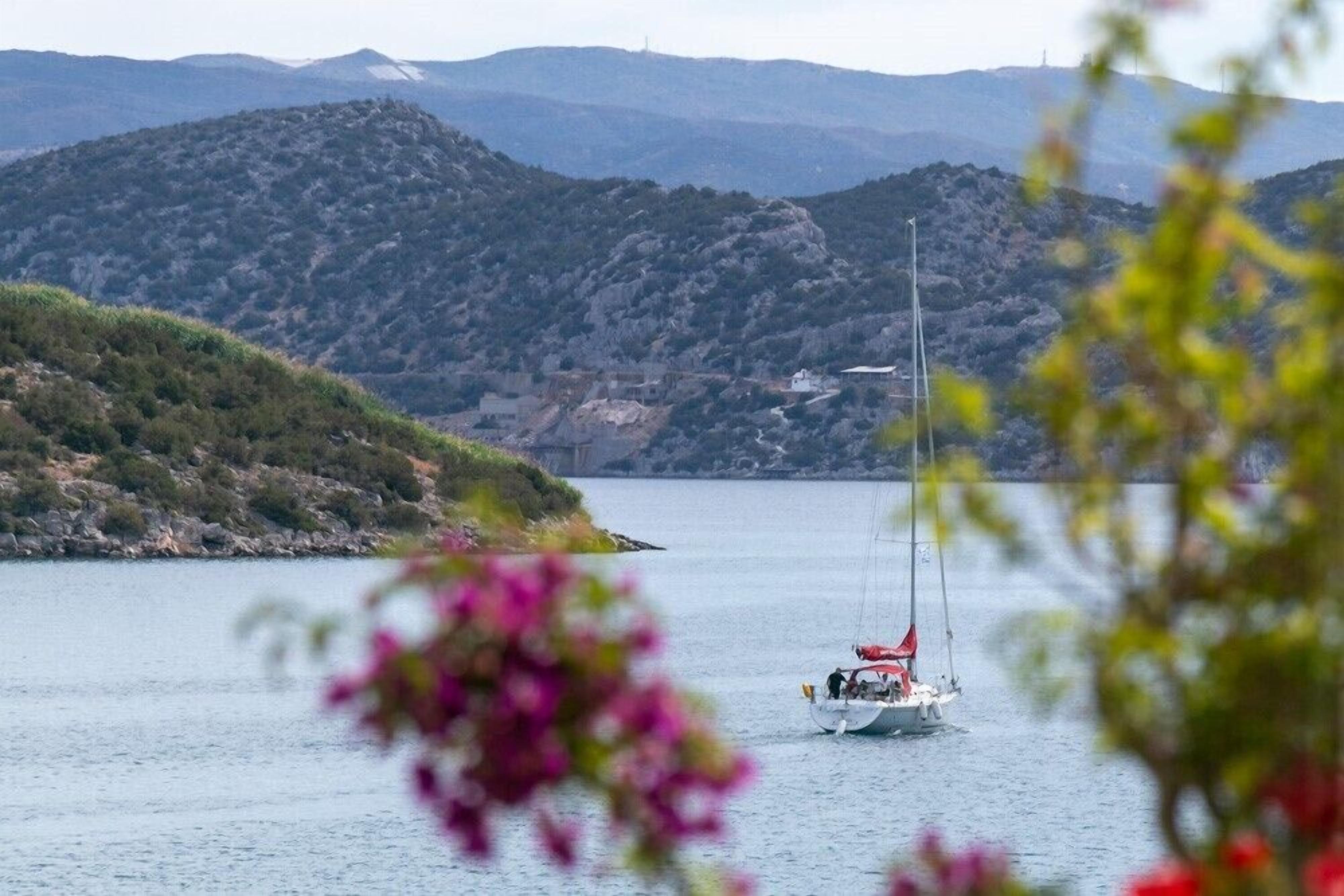 Un voilier sur un lac paisible, avec des collines en arrière-plan.