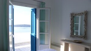 Ett sovrum med en säng, en garderob, en spegel och utsikt över havet.