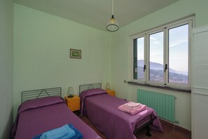 A bedroom with two beds, a window with a view, a radiator, and a hanging light fixture. - Villa With Pool in Recco Cinque Terr (Recco)