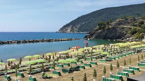 A beach with rows of beach chairs and umbrellas, rocky coastline, and a clear sky. - Villa With Pool in Recco Cinque Terr (Recco)