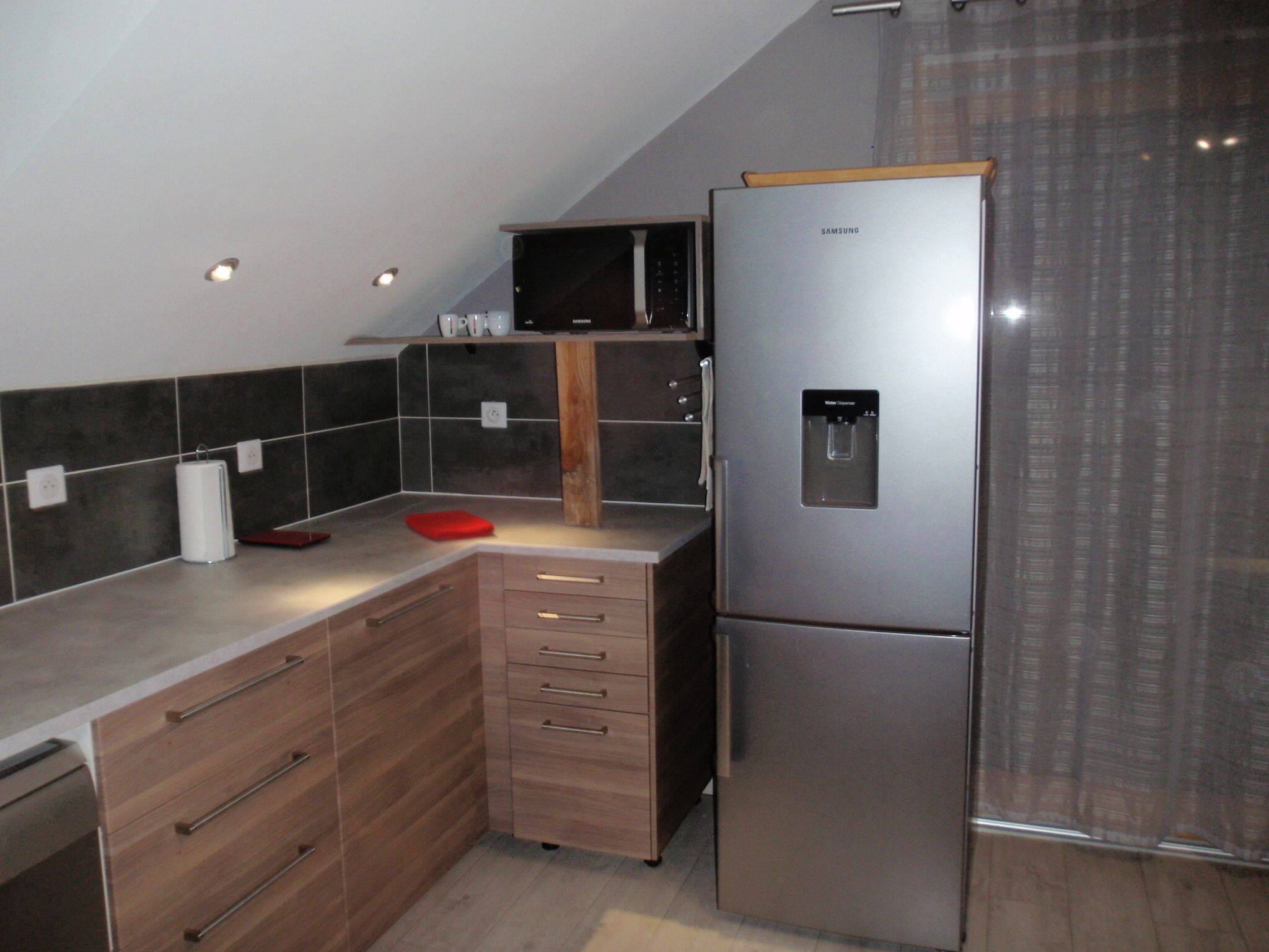Una cucina moderna con frigorifero in acciaio inossidabile, mobili in legno e dispenser per l'acqua.