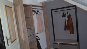 Un vestidor amplio con repisas abiertas, una barra para colgar ropa y un banco.