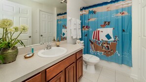A bathroom with a white sink, wooden cabinets, a toilet, and a shower curtain with a nautical theme. - Villa Close to Disney, Orlando Villa 3264 (Kissimmee)
