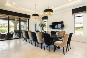 A dining area with a large table, multiple chairs, and a television mounted on the wall. - Beautiful Mansion With Private Pool, Close to Disney, Orlando Mansion 1574 (Kissimmee)