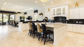 A spacious kitchen with a large island, white cabinetry, and black countertops. - Beautiful Mansion With Private Pool, Close to Disney, Orlando Mansion 1574 (Kissimmee)