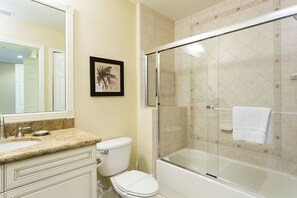 A bathroom with a glass-enclosed shower, a toilet, a sink, and a framed picture on the wall.