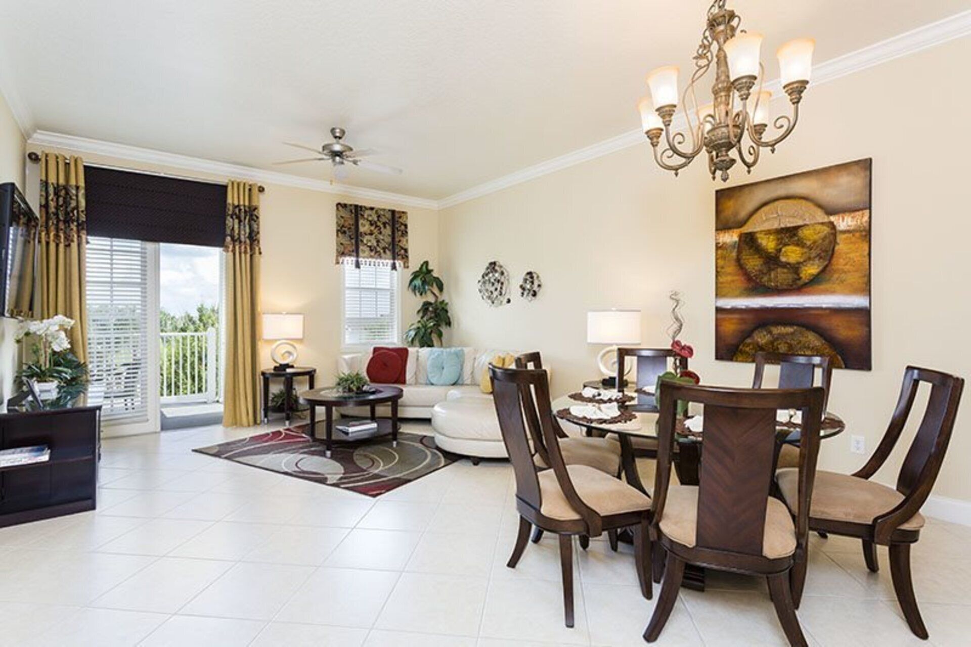 A living room with a dining area, a ceiling fan, and a chandelier.