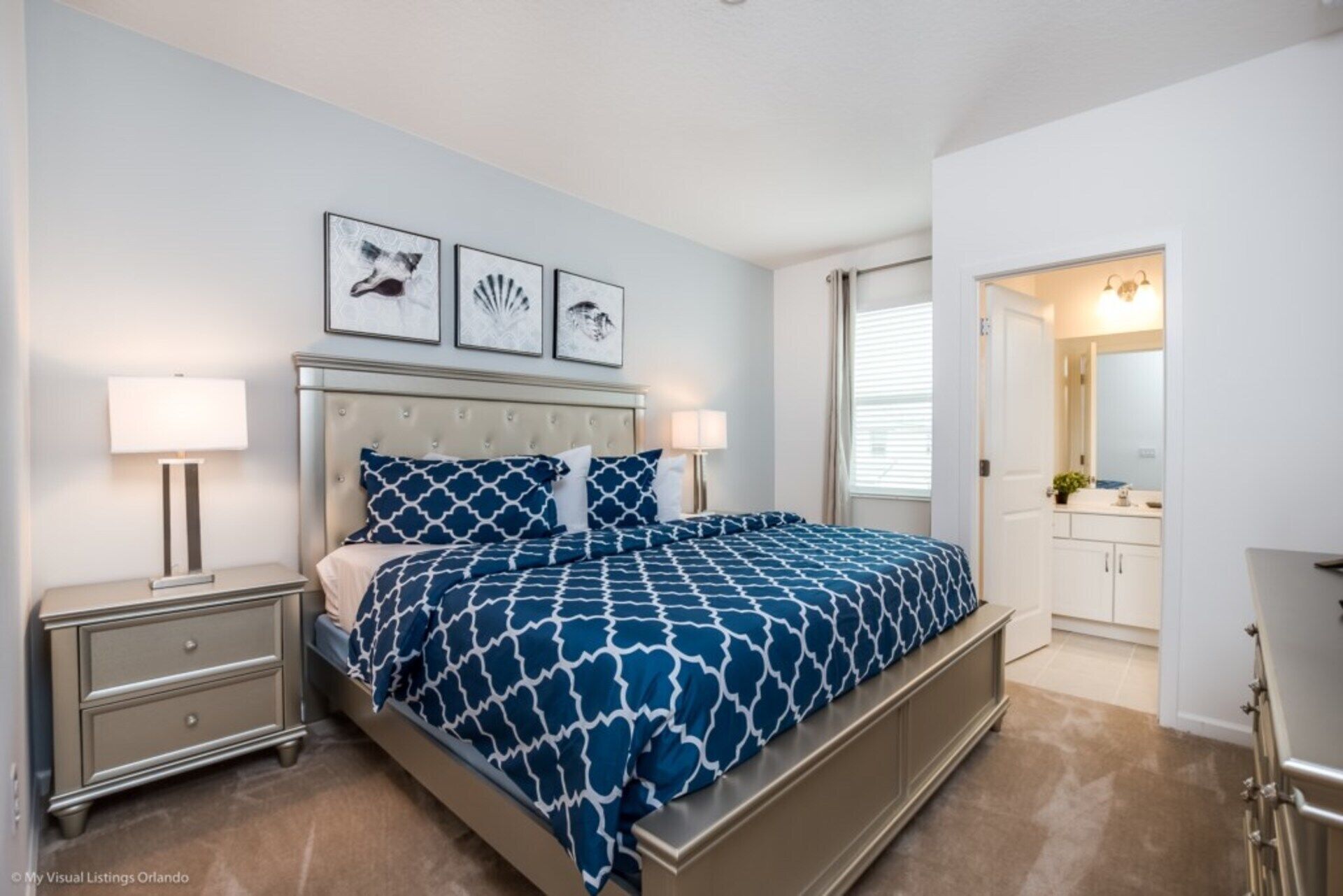 A bedroom with a bed, nightstands, a dresser, and a bathroom visible through an open door.