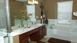 A bathroom with a double sink vanity, a large mirror, a bathtub, and a window with blinds. - Villa Close to Disney, Orlando Villa 3261 (Kissimmee)