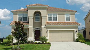A two-story house with a beige facade, a brown door, and a garage.