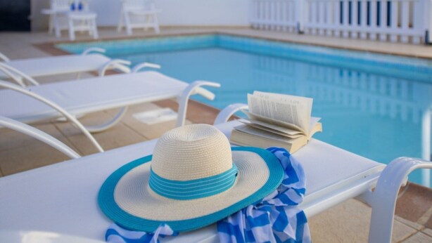 A poolside area with lounge chairs, a hat, and a book. - Beautiful Villa With Private Pool, Pernera Villa 1004 (Paralimni)