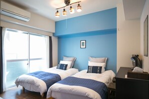 Ein Hotelzimmer mit zwei Betten, einem großen Fenster und einem Deckenventilator.