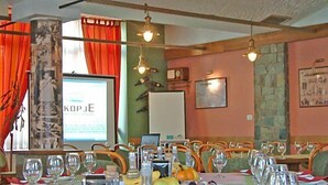 A restaurant with a long table set for dining, chairs, and hanging light fixtures. - Hotel Skopje (Skopje)