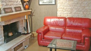 A living room with a red leather sofa, a glass coffee table, a fireplace, and a framed picture on the wall. - Hotel Skopje (Skopje)