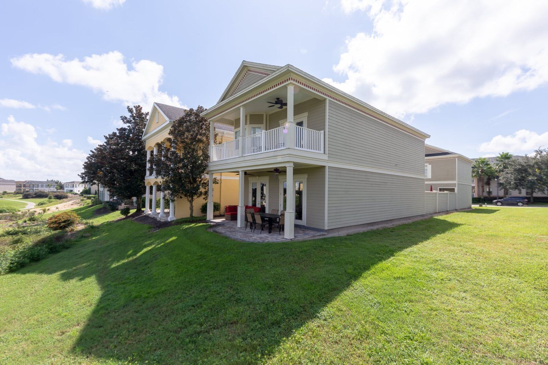A two-story house with a balcony, a covered porch, and a well-maintained lawn.