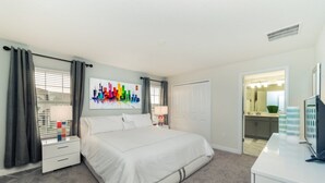 A hotel room with a large bed, a desk, a chair, a mirror, and a bathroom visible through an open door. - Rent a Luxury Townhome on Storey Lake Resort, Minutes From Disney, Orlando Townhome 1004 (Kissimmee)