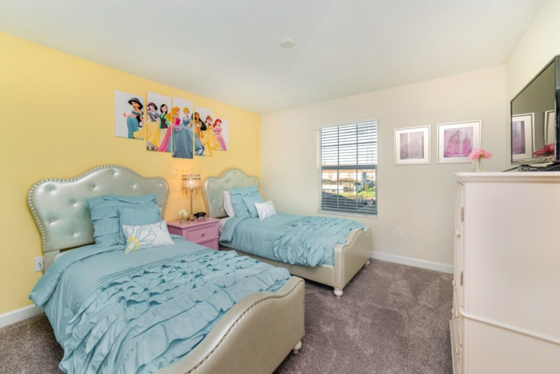 A bedroom with two beds, a nightstand, a dresser, and a window with blinds.