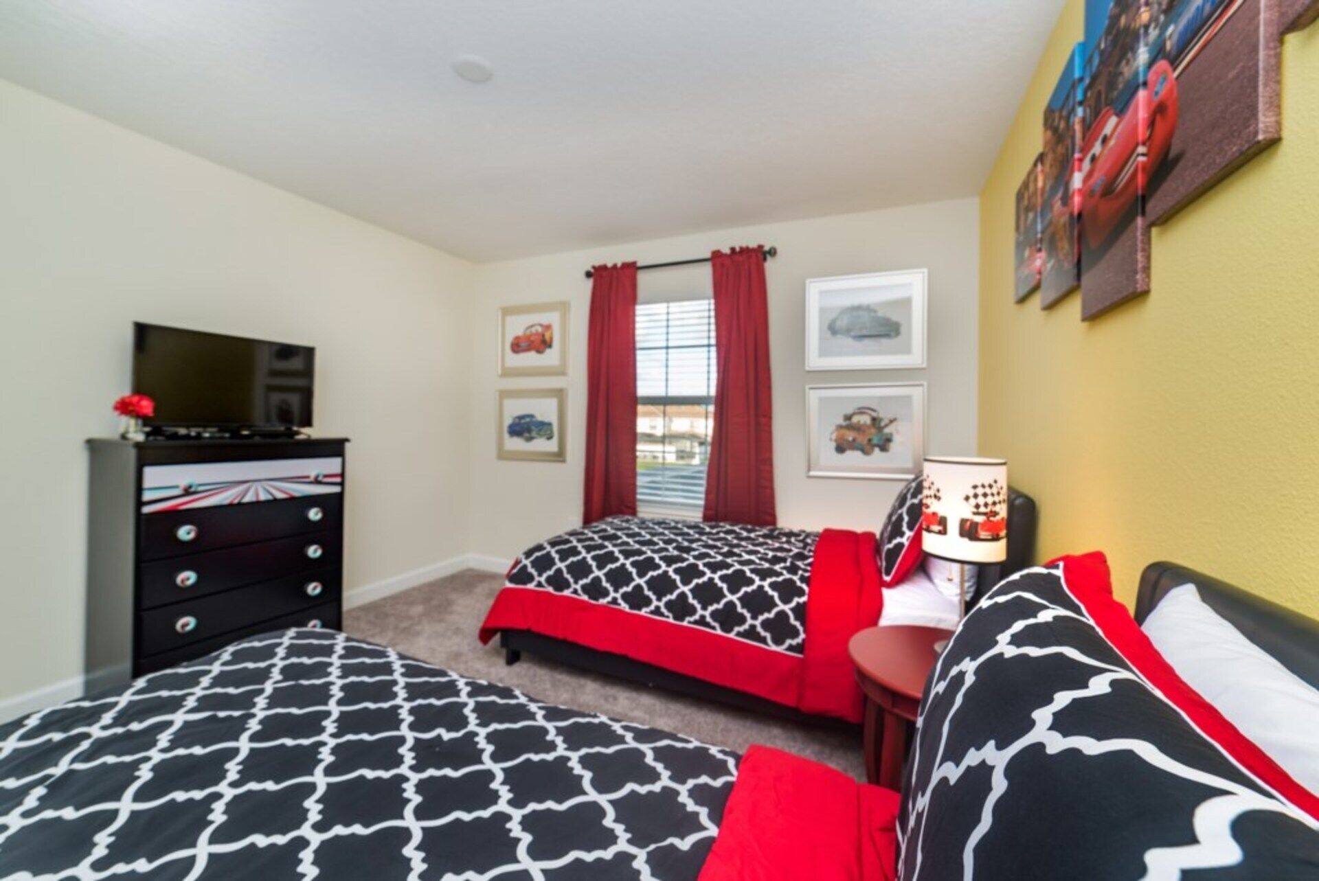 A bedroom with two beds, a TV, a dresser, and a window with curtains.