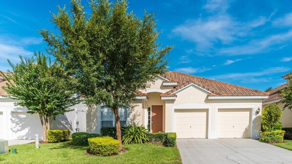 A residential house with a garage, a driveway, and well-maintained landscaping.