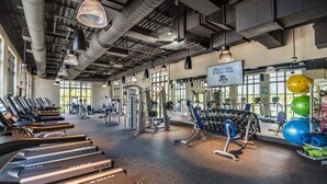 Une salle de sport équipée de tapis de course, d’appareils de musculation et de poids libres.