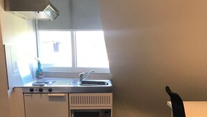 Een kleine keuken met een kookplaat, magnetron en spoelbak.