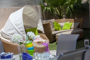 Relax in a serene outdoor space with a sofa, chairs, and a table, perfect for reading and enjoying a cup of tea.