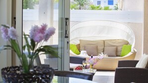 A patio area with wicker furniture, a glass table, and a view of a building through a glass door. - Beautiful Villa With Private Pool, Protaras Villa 1028 (Paralimni)