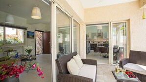 A modern living room with a sofa, a coffee table, and a dining area visible through glass doors. - Beautiful Villa With Private Pool, Protaras Villa 1028 (Paralimni)