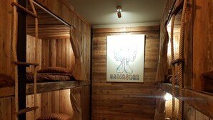 A wooden cabin room with bunk beds and a poster on the wall. - Cozy Cabin - Hostel (Bangkok)